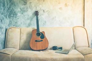 Guitar with laptop and headphone on a sofa. Vintage tone.