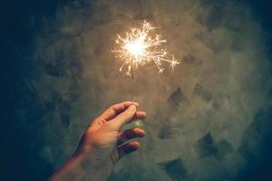 Close up of hand holding sparkler on grunge background photo