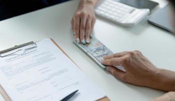 hombre de negocios dando dinero, dólares en efectivo a su socio sobre un escritorio de oficina - conceptos de préstamo, pago y soborno foto