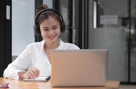 close up of Student learning online class by using laptop computer and writing notebook at workplace, E learning and online working concept. photo