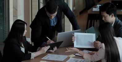 Business people showing team work while working in board room in office interior. People helping one of their colleague to finish new business plan. Business concept. Team work. photo