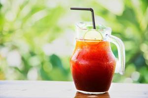 Ice tea on wooden table over green garden background - relax with beverage in nature concept photo