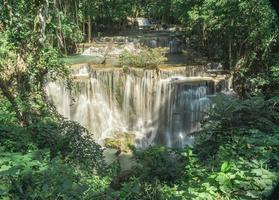 muchas cascadas fluyen en el marco de plantas y árboles verdes. mirador de la cascada huai mae kamin, provincia de kanchanaburi foto