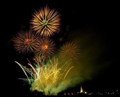 Fuegos artificiales enormes y coloridos sobre los campos de arroz al anochecer. foto