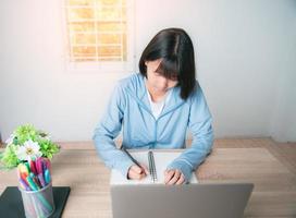 a young girl is writing down her notebook. photo