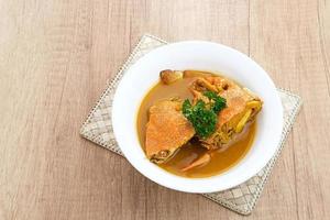 Kepiting Saus Padang, Crab with Padang Sauce, spicy and savory. Served in white bowl. photo