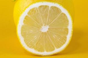 vista de cerca de la rebanada madura texturizada de cítricos de limón aislada sobre fondo amarillo. rodaja de limón con trazado de recorte para el diseño de concepto de alimentos saludables foto