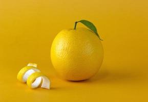 una fruta de limón amarillo con una hoja y una rodaja de cáscara aislada en un fondo amarillo foto