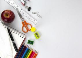 Education elements concepts, color pencils, face mask, paper clips, scissors, ruler, apple isolated on white background. Back to school concept photo