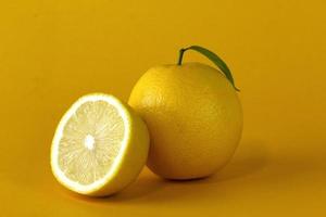Organic lemon fruits and a Lemon slice with leaf isolated on yellow background photo