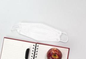 Back to school concept with education materials, face mask, note book, apple, pen isolated on white background. Top view concepts template photo