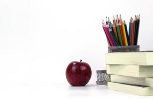 elementos educativos en la caja con manzana roja y libros aislados en fondo blanco. diseño de plantillas de concepto de regreso a la escuela foto