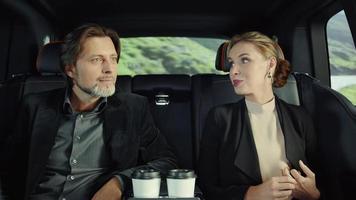 Rolls-Royce passengers, a man and a woman drink coffee.The road along the mountains video