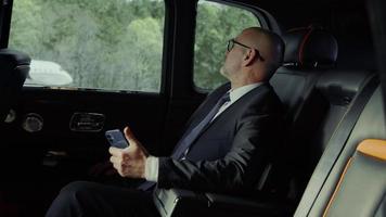 Rolls-Royce-Passagier in einem Business-Anzug mit einem Telefon auf der Landebahn des Flughafens video