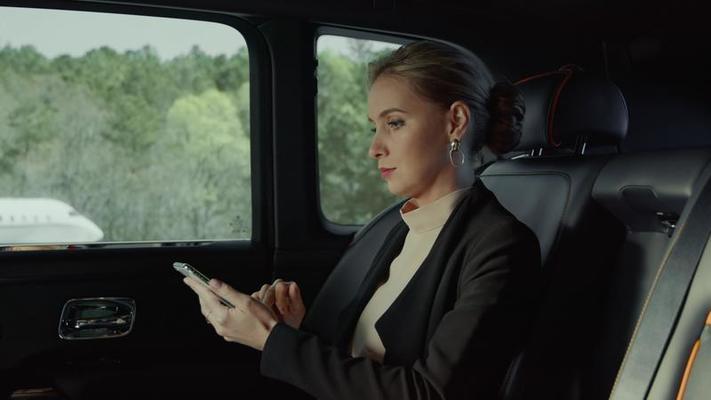 The passenger of the RollsRoyce is a girl sitting in the backseat  looking at something on the phone smiling Airport runway 10147204 Stock  Video at Vecteezy