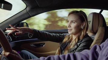 A passenger of a luxury Bentley car points to the driver with his hand. A road in the mountains.Mountain background video