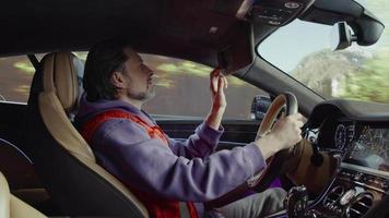 o motorista de um Bentley de luxo, puxa a viseira de sol, olha no espelho e fecha o set.mountain background video