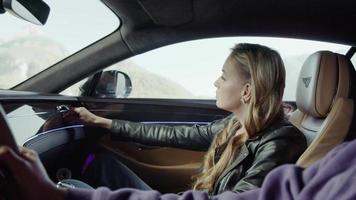 The girl, a passenger of the Bentley, corrects the air duct grille. Background of the mountain, flashing trees video