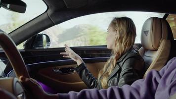 la niña, pasajera del bentley, vio algo en la ventana y se lo muestra al conductor. fondo de la montaña, árboles parpadeantes video