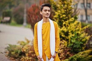 Indian stylish man in yellow traditional clothes with white scarf posed outdoor. photo