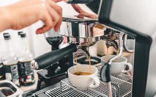 extracción de café de la máquina de café barista profesional. espresso que se vierte de una máquina de café en una taza de café en una cafetería. foto