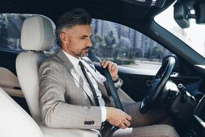 hombre confiado abrochándose el cinturón de seguridad mientras se sienta en el asiento delantero de un auto foto