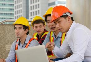 Engineering team working together on building site and using laptop for project progress photo
