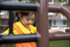 Asian happy girl with orange dress is playing in the playground. photo