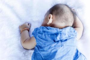 A beautiful 6 month old baby with big eyes lies on the bed. photo