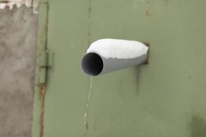Pipe in wall. Draining water from sewer. Water conduit on street. photo