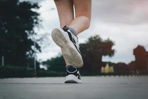 Close up of young  woman shoes walking outdoors in running shoes from behind. photo