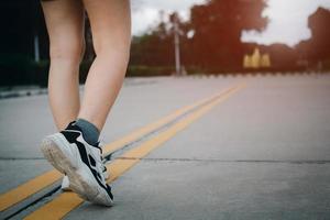 primer plano de zapatos de mujer joven caminando al aire libre en zapatos para correr desde atrás. foto