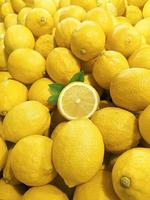 Ripe slice of yellow lemon citrus fruit with leaves on Ripe Yellow Lemons background photo