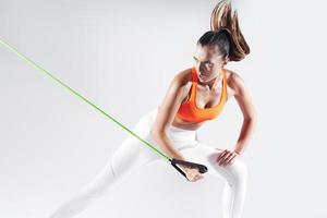 Concentrated young woman exercising with resistance band against white background photo