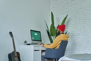 Young African man using computer while sitting at his working place at home photo