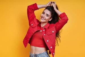 Beautiful young woman adjusting her hair against yellow background photo