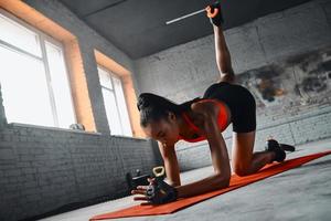 joven africana concentrada haciendo ejercicios de estiramiento en el gimnasio foto