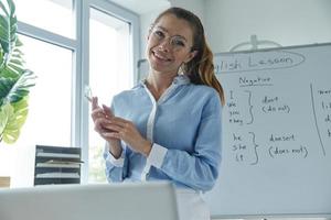 Confident young woman looking at camera while standing near the whiteboard at the classroom photo