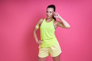 Confident woman in sports clothing wearing captain band and gesturing against pink background photo