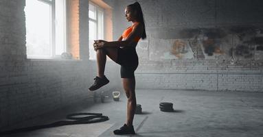 Confident young woman in sports clothing warming up before training in gym photo