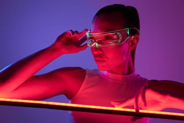 bella mujer con gafas futuristas apoyada en la lámpara led sobre fondo  oscuro 10154145 Foto de stock en Vecteezy