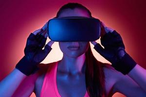 Young woman wearing virtual reality glasses against colorful background photo