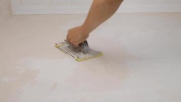 Der Meister reibt die verputzten Wände mit Sandpapier von Hand video