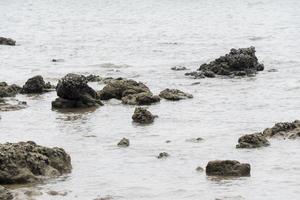 rocas junto al mar por la tarde el mar circundante se refleja en blanco. foto