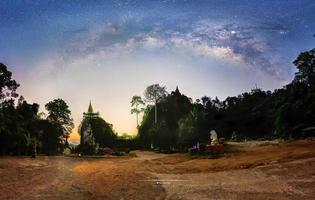 panorama, la vía láctea sobre la sombra del árbol durante el crepúsculo antes del amanecer, pagoda en la cima de la colina foto