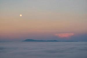 Full moon falling And the mist in the morning time. The color orange sky reflects the sun's rays. photo