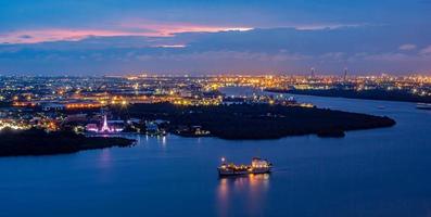 Street lights and street lighting from residential houses in the suburbs during sunset time, boat traffic on the Chao Phraya River, Samut Prakan, Thailand photo