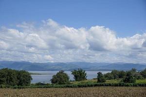 cielo azul claro nubes blancas, árboles, árboles de hierba natural alrededor del embalse de srinakarin, kanchanaburi, tailandia foto