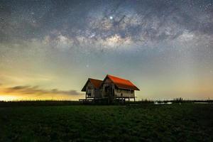 Milky Way , old abandoned house, red roof on open field photo