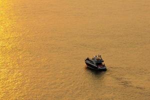 la puesta de sol en la superficie del mar refleja el sol en oro. el parque turístico el barco para ver la belleza del sol. foto